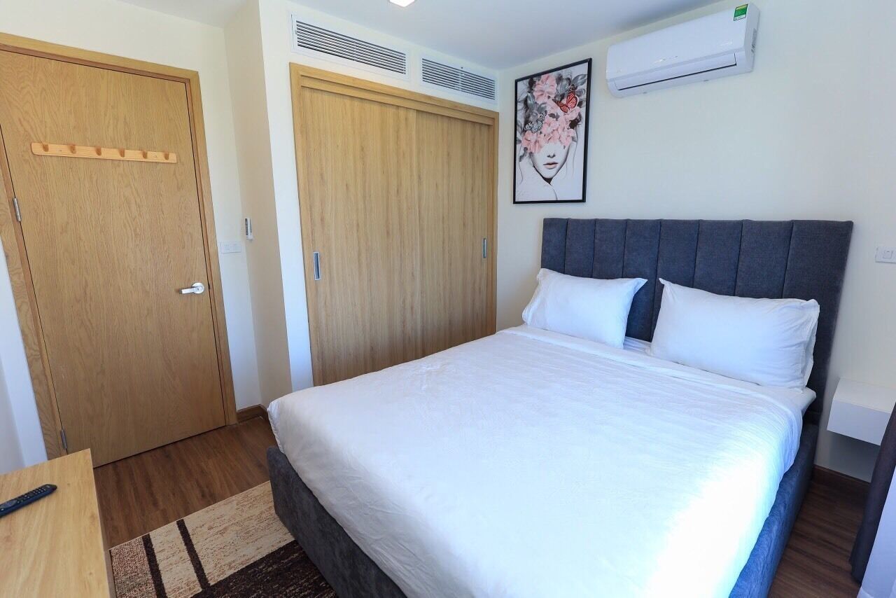 A bedroom with a bed, wooden wardrobe, and an air conditioning unit.