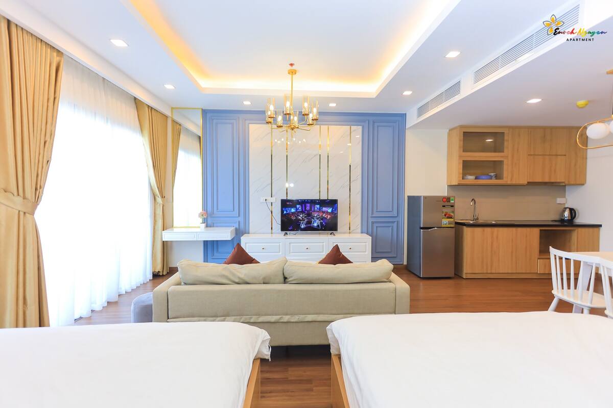Ein modernes Hotelzimmer mit Schlafsofa, Fernseher, Küchenzeile und Esstisch.