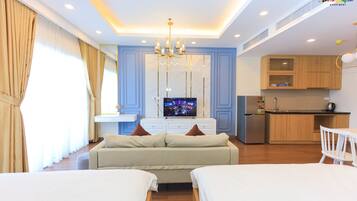 Une chambre d’hôtel moderne équipée d’un canapé-lit, d’une télévision, d’un coin cuisine et d’une table à manger.