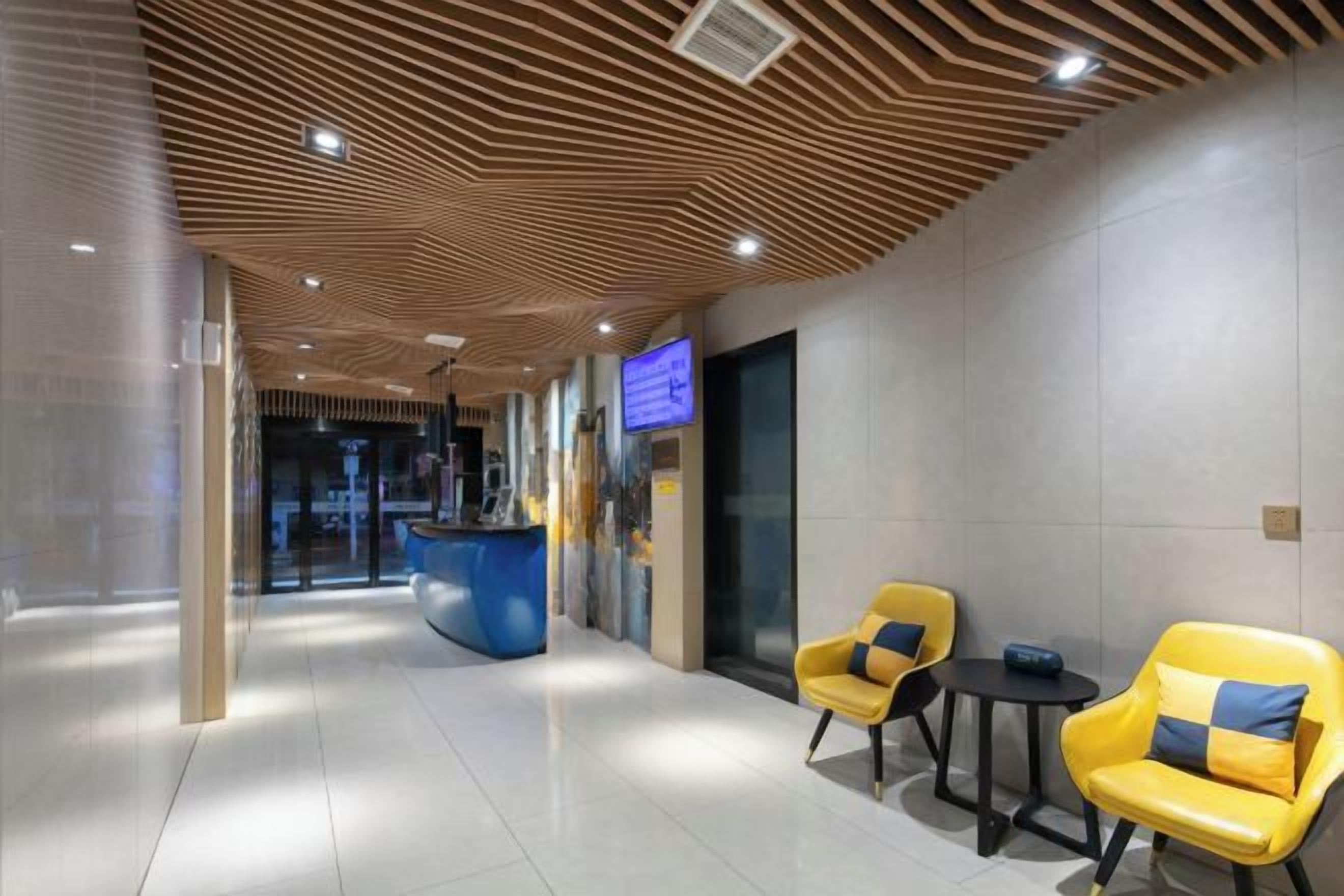 A hotel lobby with a reception desk, seating area, and a modern ceiling design.