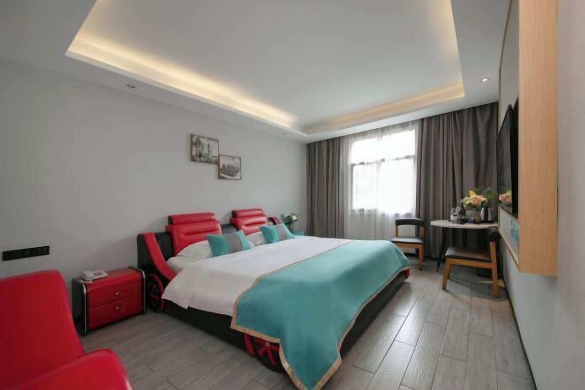 A modern hotel room with a large bed, a desk, and a chair.
