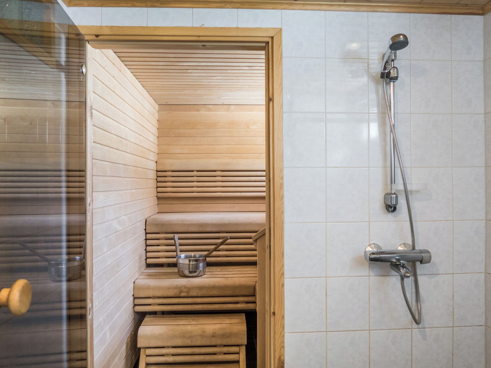 Un sauna avec des bancs en bois et une pomme de douche.