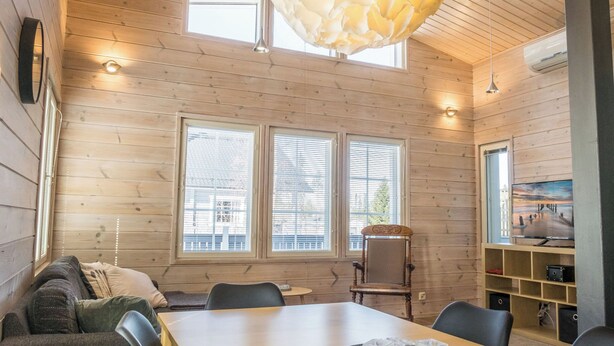 A cozy cabin interior with a wooden interior, a dining table, chairs, a sofa, and a large window with blinds. - Pikku-pölly by Interhome (Sotkamo)