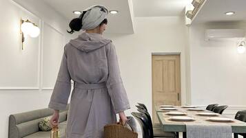 A person walking towards a dining area with a table set for a meal, a sofa, and a door in the background.