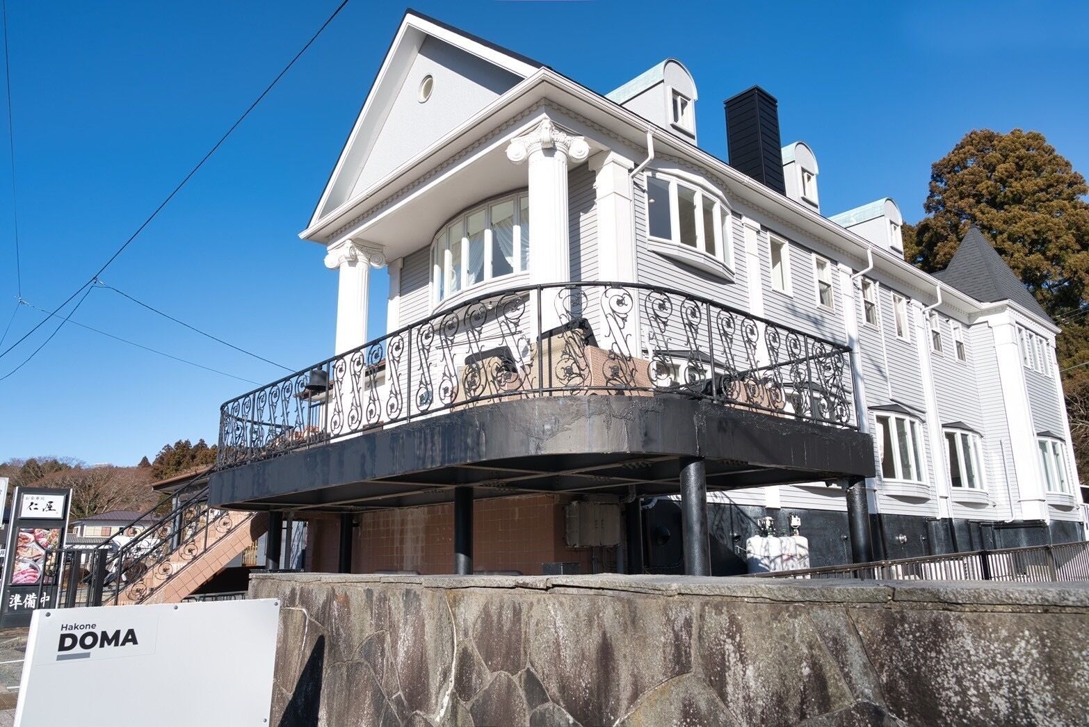 A white building with a balcony and a sign reading 'Hakone DOMA'.