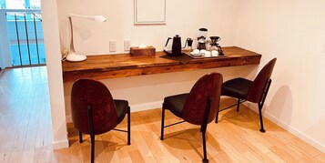 Una zona de cocina con encimera de madera, dos sillas, cafetera y lámpara.