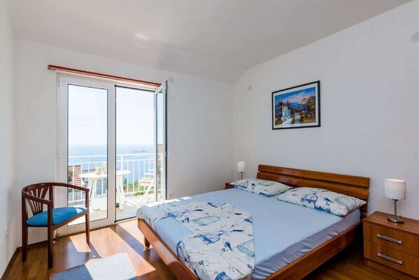 Une chambre à coucher comprenant un lit, une chaise, une table de chevet et une vue sur l’extérieur grâce à une porte coulissante.