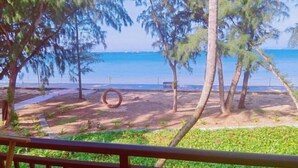 A beach view with trees, a tire swing, and a bench.