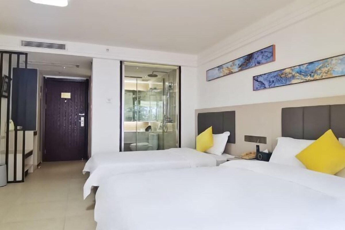 Ein Hotelzimmer mit zwei Betten, einer Duschkabine aus Glas und Bildern an den Wänden.