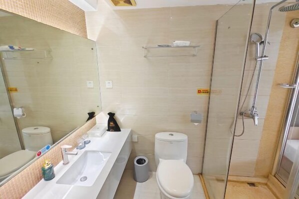 A bathroom with a white sink, mirror, toilet, and shower.