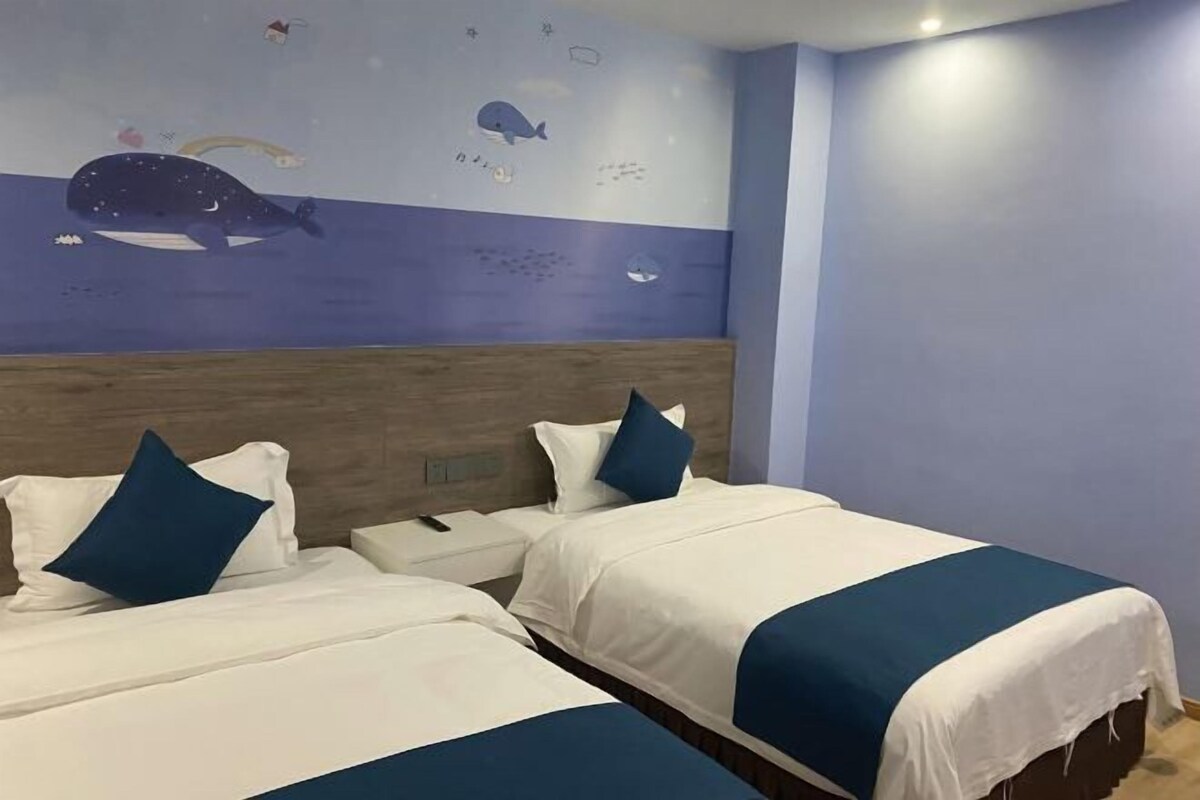 A hotel room with two beds, a wooden headboard, and a wall mural of sea creatures.