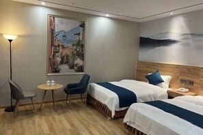A hotel room with two beds, a small round table, two chairs, a lamp, and a large painting on the wall. - Zizhongchuan East Business Hotel (Zizhong)