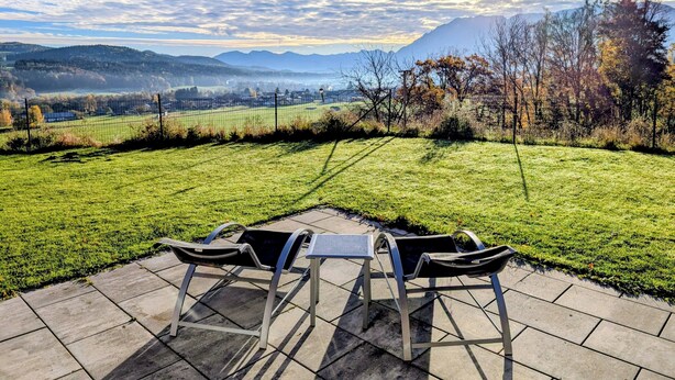 A patio with a table and chairs overlooking a grassy field and distant mountains. - Suite "bergsehnsucht" bis zu 5 Personen, ca. 65 m² (Anger)