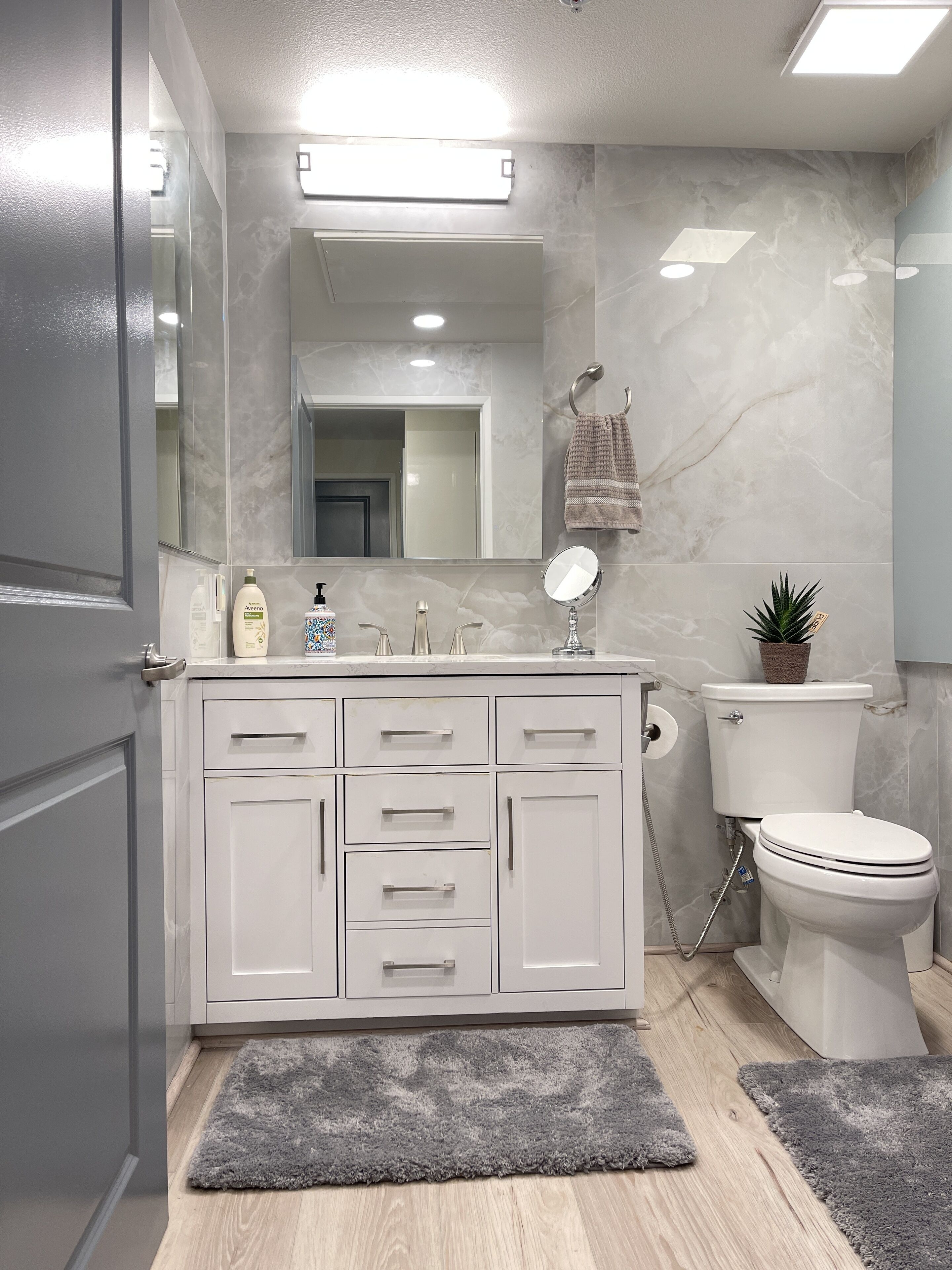 Un baño moderno con un tocador blanco, un inodoro y un espejo.