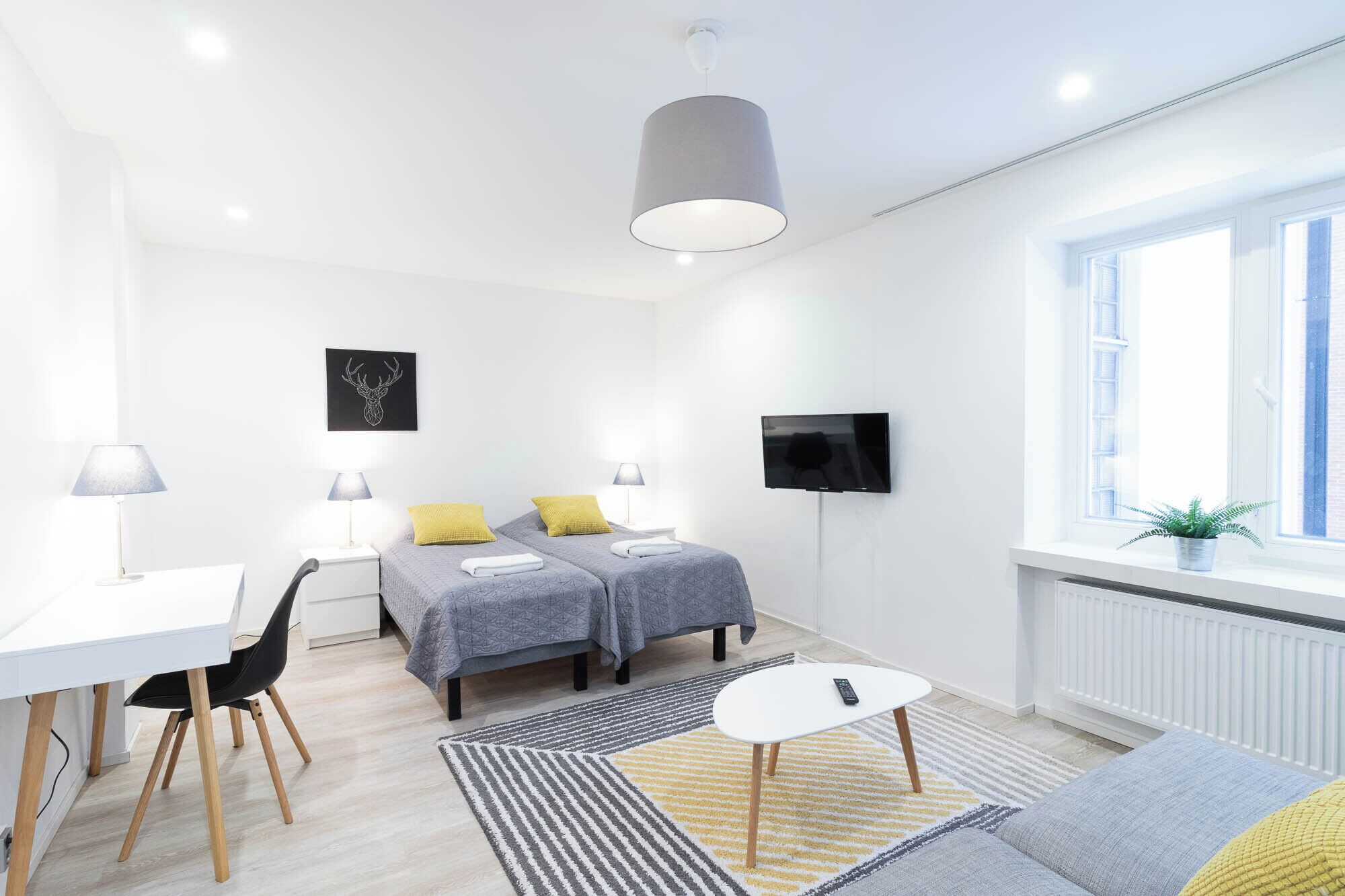 Una habitación moderna y luminosa con dos camas, un escritorio y un televisor.