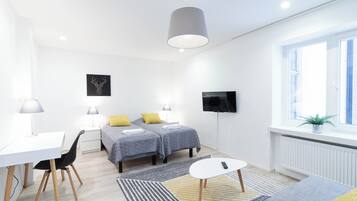 Una habitación moderna y luminosa con dos camas, un escritorio y un televisor.