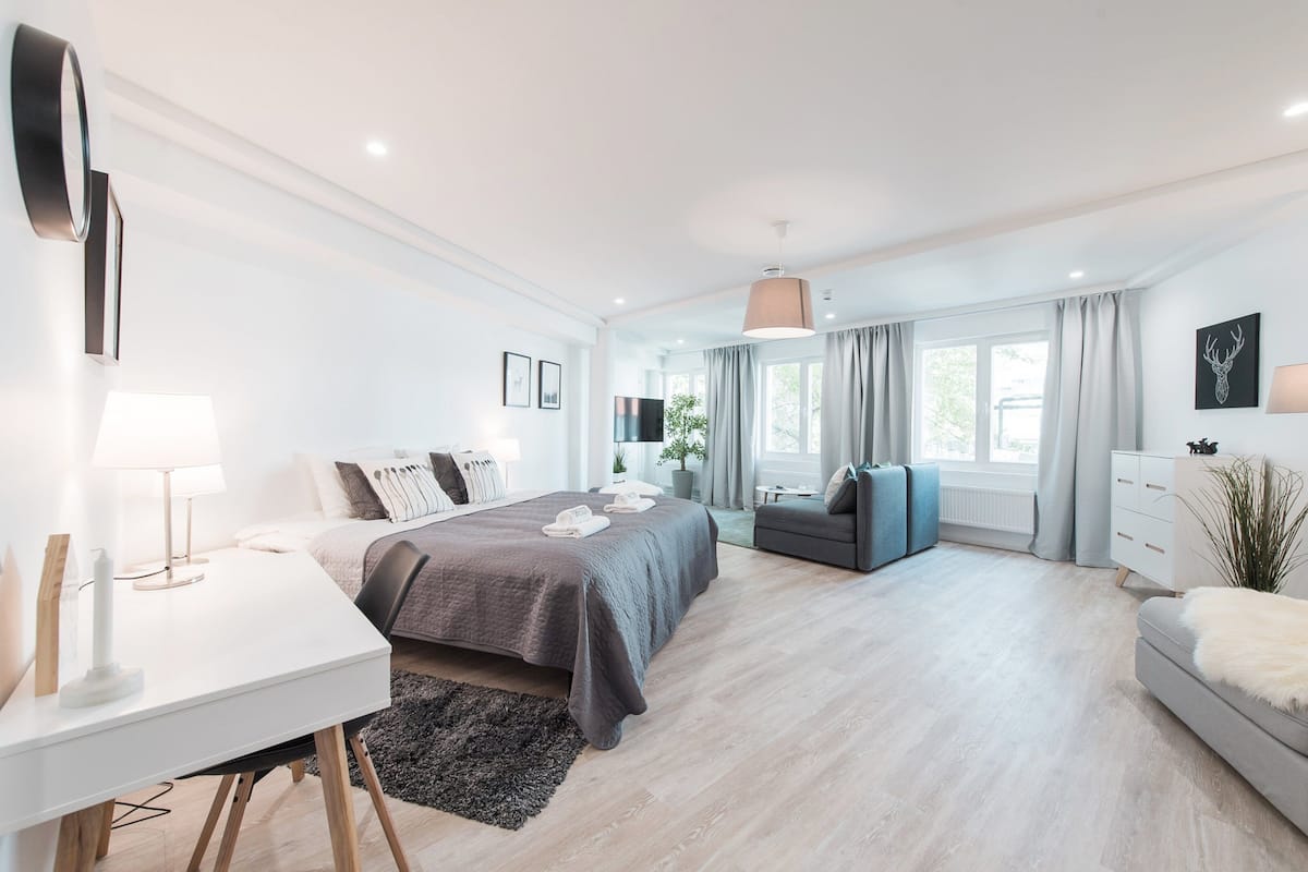 Une chambre moderne avec un lit, une table de chevet, une lampe et une vue sur l’extérieur.