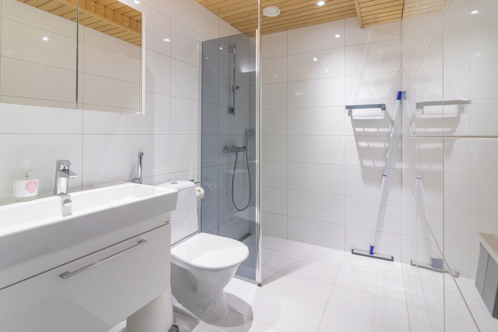 Un bagno moderno con cabina doccia in vetro, lavabo bianco e water.