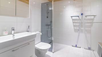 Un bagno moderno con cabina doccia in vetro, lavabo bianco e water.