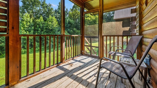 Una terraza de madera con barandilla, un espacio cubierto con ventana y una silla.