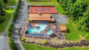 Un resort con cancha de tenis, múltiples piscinas y zonas de descanso.