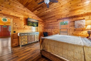 Ein Holzhütten-Innenraum mit einem Bett, einem Schminktisch und einem Bild an der Wand.