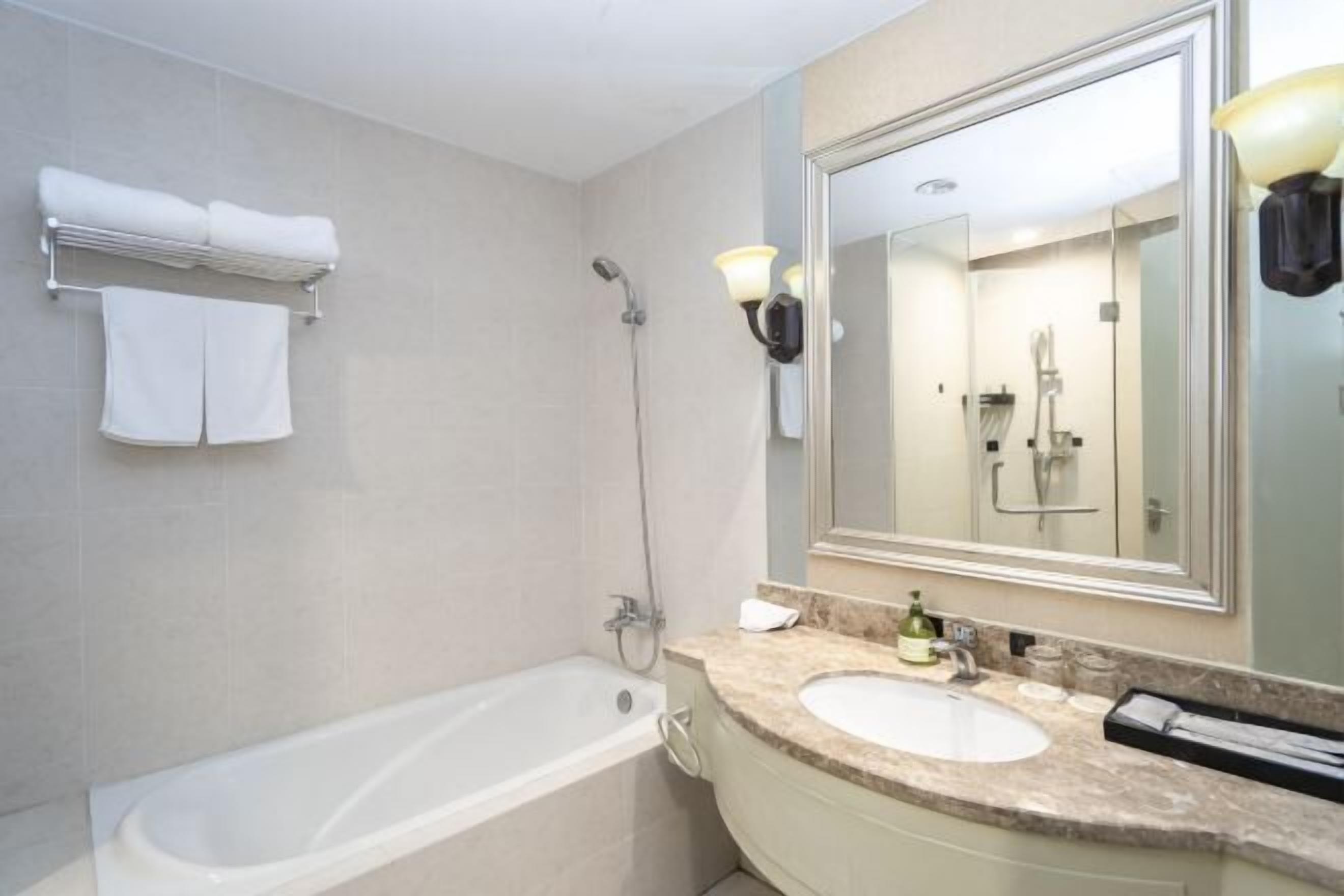 A modern bathroom with a bathtub, a sink, and a large mirror.