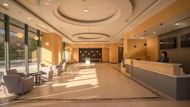 A spacious lobby with a reception desk, seating area, and large windows allowing natural light. - Zexi Business Hotel (Taicang)