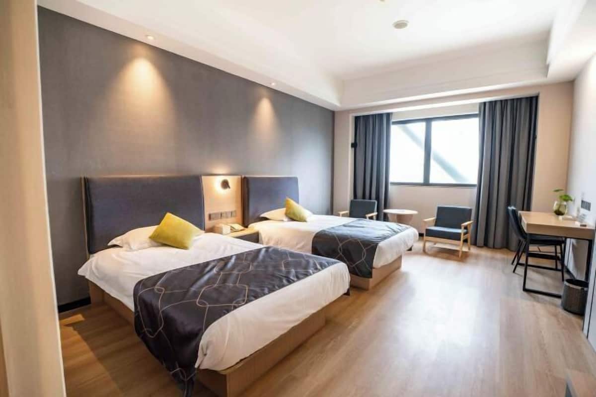 A hotel room with two beds, a desk, and a chair.