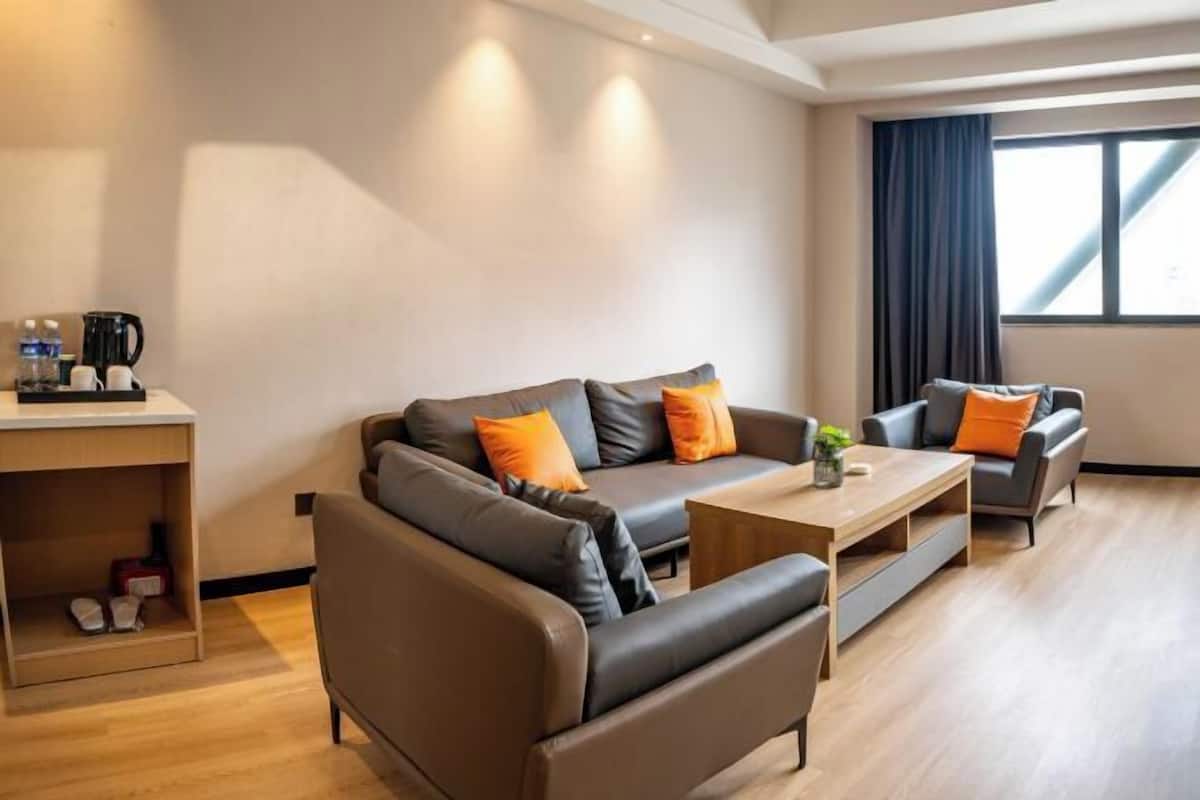 A modern living room with a sofa set, a coffee table, and a small side table with a kettle and cups.