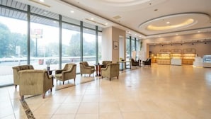 A spacious lobby with large windows, comfortable seating, and a display counter. - Zexi Business Hotel (Taicang)