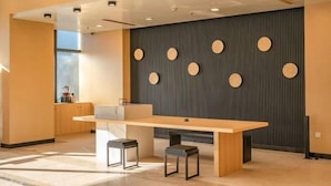 A modern kitchen with a wooden table, two stools, and a wall with circular decorations. - Zexi Business Hotel (Taicang)