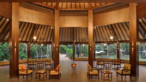 Un vaste espace intérieur doté de poutres en bois et de grandes fenêtres offrant une vue sur la verdure.