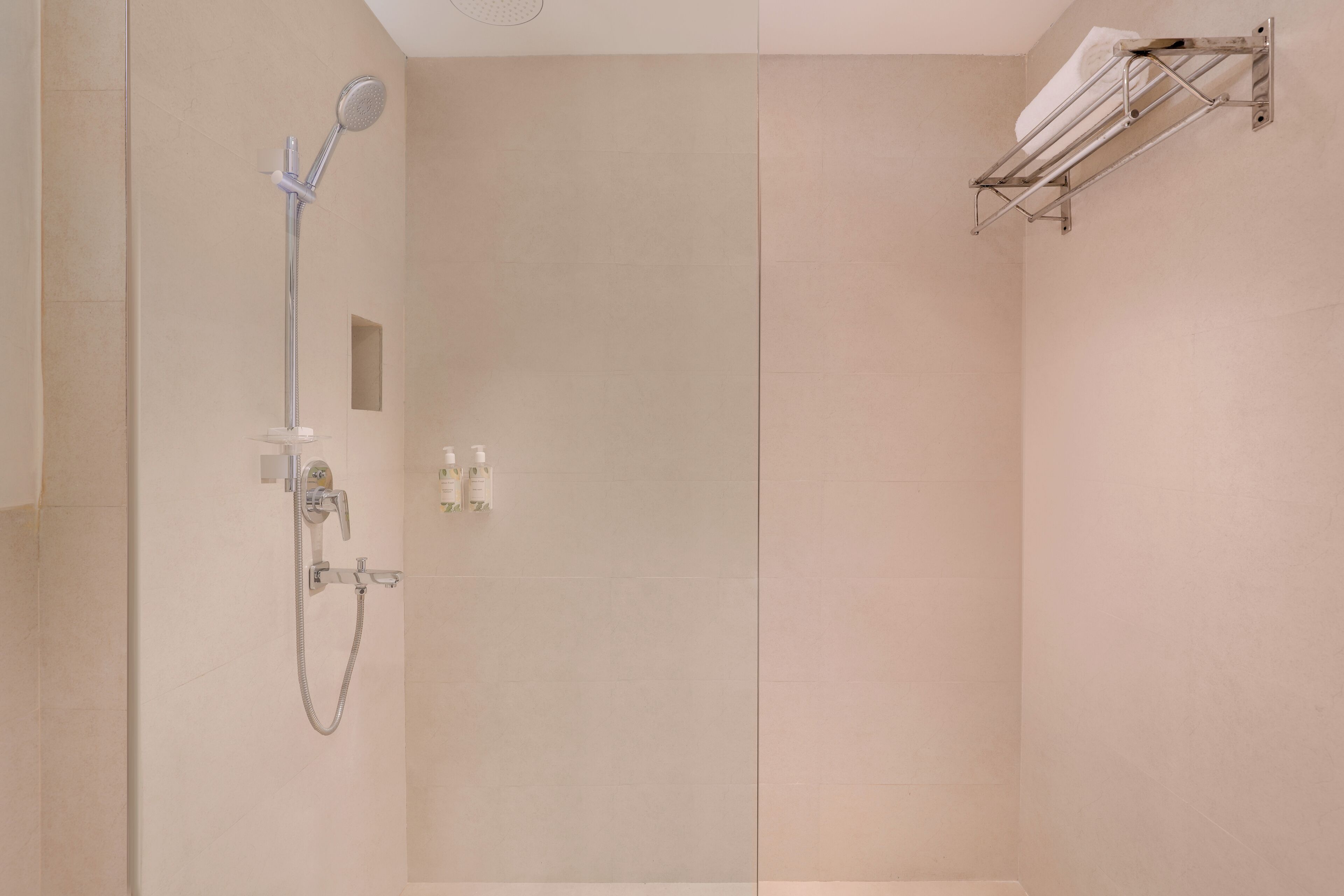Un baño moderno con ducha, toallero y un pequeño estante con artículos de aseo.