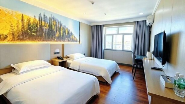 Una habitació d'hotel amb dos llits, un escriptori, una televisió i un quadre a la paret.