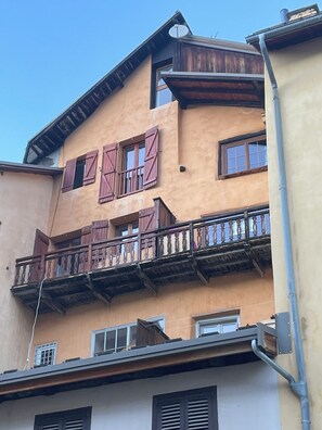 A multi-story building with balconies, wooden shutters, and a satellite dish. - Appartement Épuré Dans la Veille Ville de Briançon Avec Balcon et vue (Briançon)