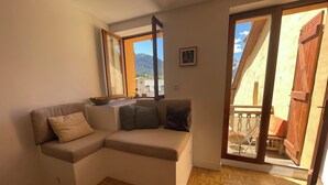 Ein gemütliches Wohnzimmer mit einer Eckcouch, einem Fenster mit Bergblick und Holzboden.