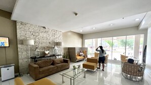 A spacious living area with a stone wall, a sofa, a coffee table, and a view of the outside. - IT Park Studio w/ washing machine (Cebu City)