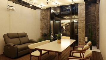 A patio with a sofa, table, and chairs, a projector, and a brick wall.