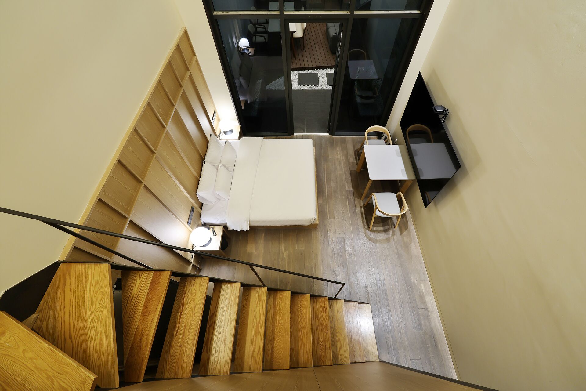 Uma escada leva a um quarto com uma cama, uma mesa e cadeiras.