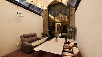 A modern patio with a dining table, chairs, a sofa, and a potted plant.