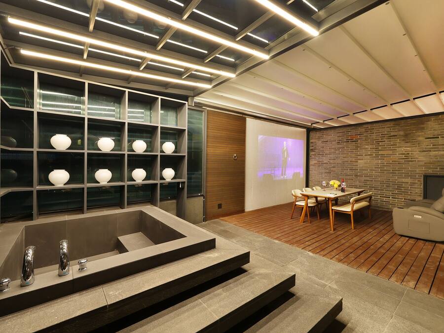 A modern interior with a stone bathtub, a projection screen, and a brick wall.
