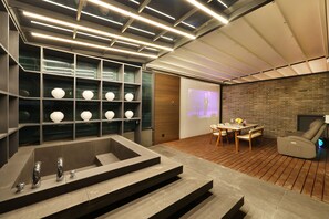 A modern interior with a stone bathtub, a projection screen, and a brick wall. - Brown Dot Hotel Dongtan (Hwaseong)