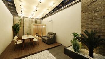 A modern interior with a wooden table and chairs, a cushioned seating area, and a brick wall.