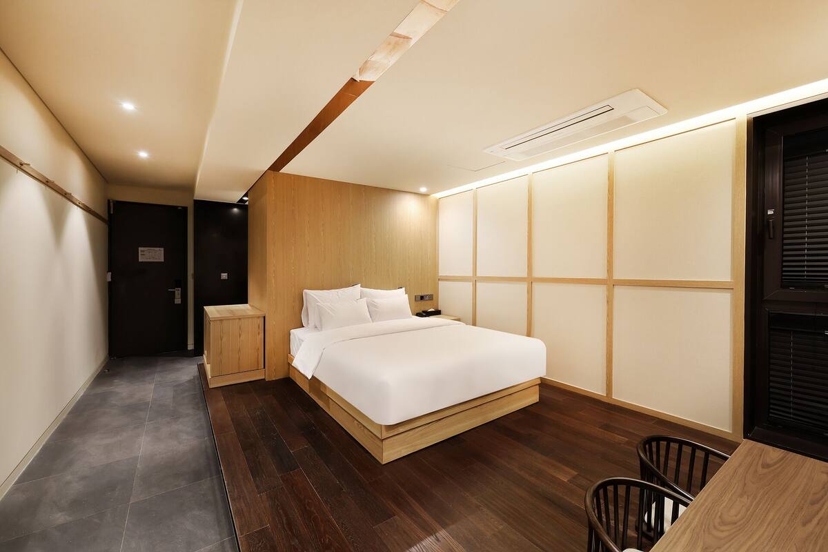 A bedroom with a bed, bedside table, and a small wooden cabinet.