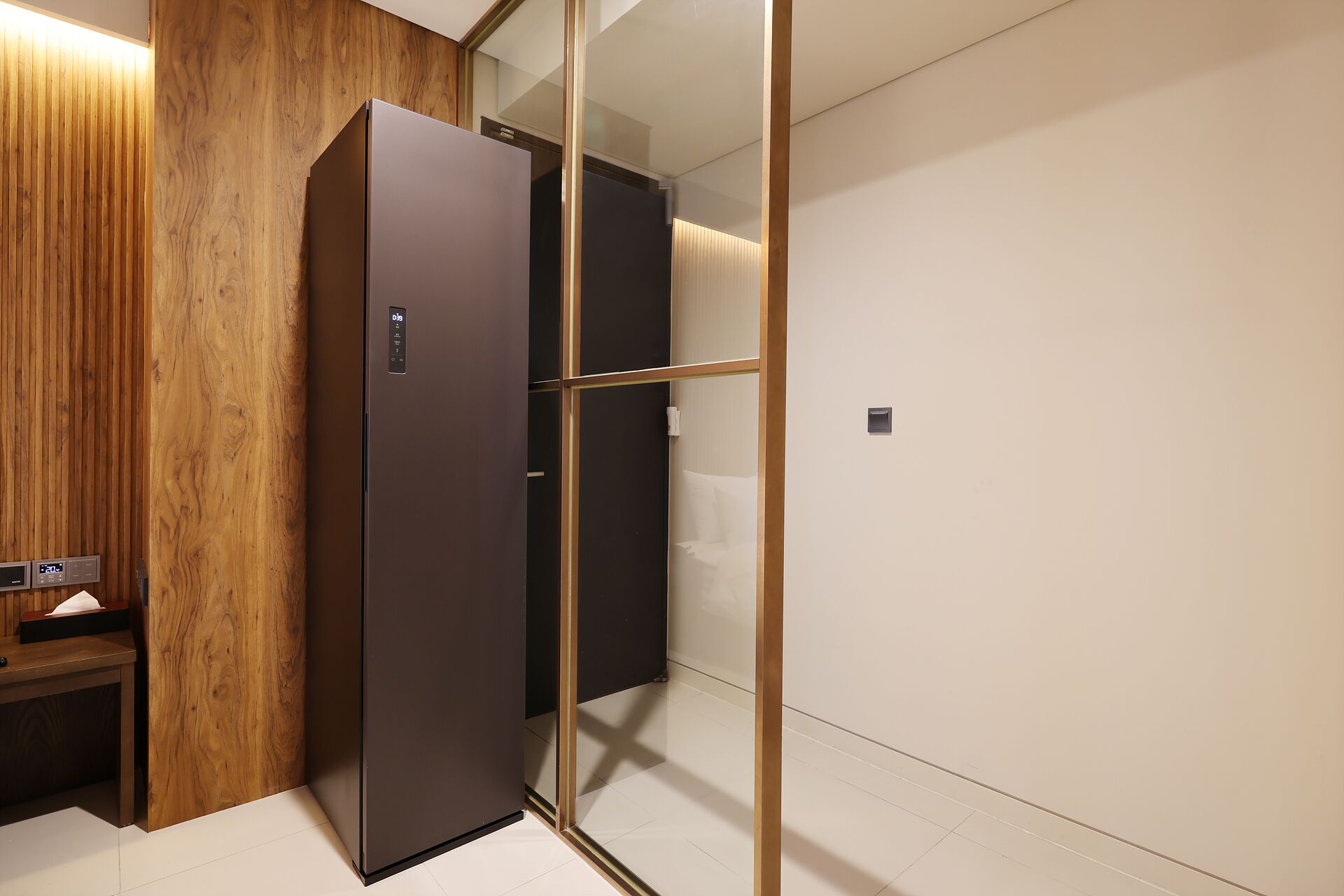 Et moderne hotelværelse med en væg af træpaneler, en mørk garderobe og en glasvæg.