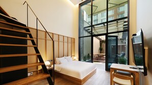 Una camera da letto moderna con una scala in legno, un letto grande, una scrivania e vista all'esterno.