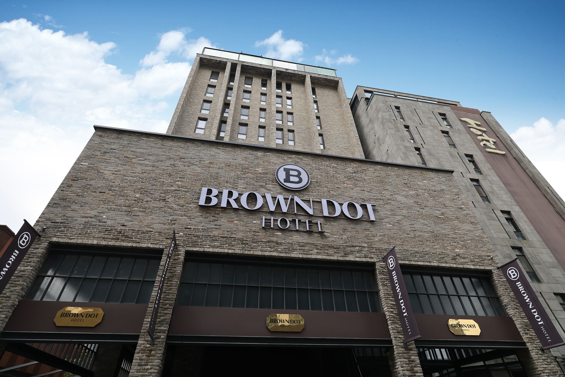 En bygning med et skilt, der viser 'BROWN DOT HOTEL', og et logo over skiltet.