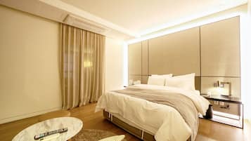A hotel room with a bed, a bedside table, a remote control, a small table, and a window with curtains.
