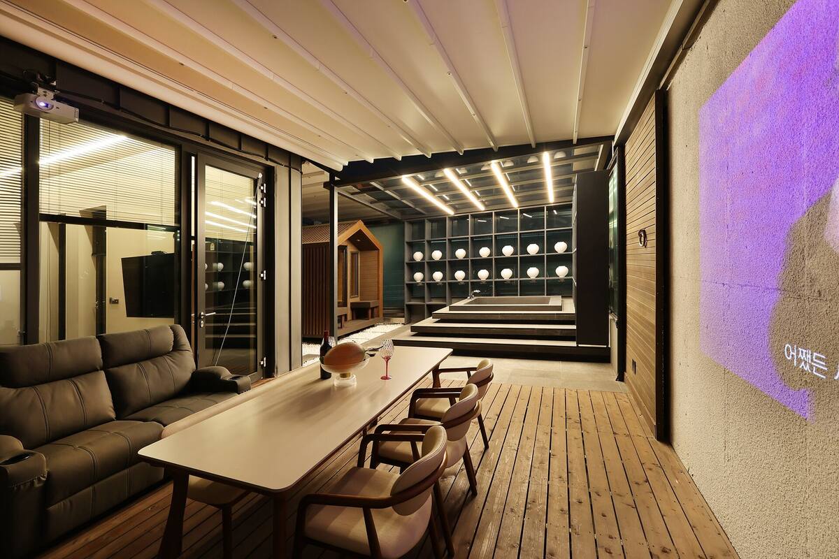 A modern interior with a wooden deck, a sofa, a table, and a projection screen.